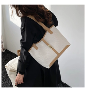 Close-up of contrast color tote bag featuring woven texture and gold metal buckle