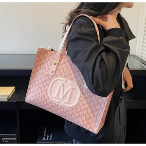 Detail of pink tote bag with M monogram pattern and round logo on modern indoor background