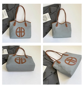 Detail view of large grey woven tote bag with brown straps and circular B logo