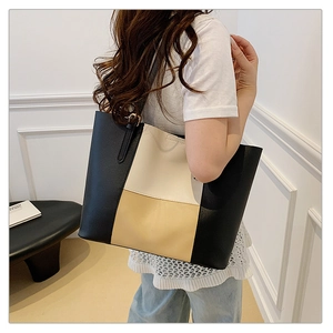 Detail of a large color-block tote bag in black, cream, and tan with pebbled faux leather texture
