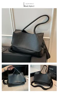 Detail view of black leather tote bag showing grainy texture and wide woven strap