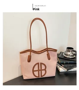 Pink woven tote bag with brown leather handles and large round AB letter patch detail