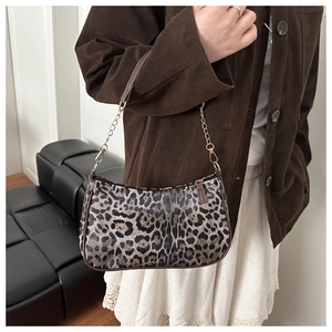 Dettaglio borsa leopardata con tracolla in pelle marrone e dettagli a catena dorata