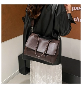 Model wearing dark brown vintage leather tote bag with top handles and shoulder strap