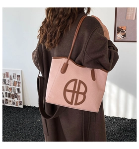 Pink woven tote bag with dark brown leather handles shown on a shoulder in daily use