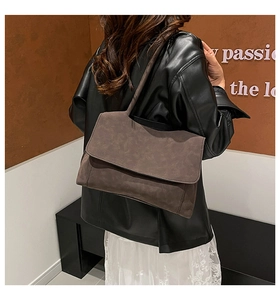 Close-up of a vintage dark brown suede shoulder bag featuring a matte flap design