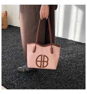 Close-up of pink fabric and brown leather patchwork tote bag with a circular logo detail