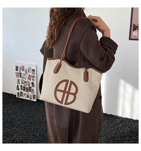 Detail of a large woven tote bag with brown leather trim and circular logo patch