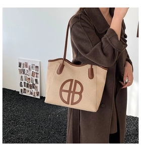 Close-up of woven tote bag with brown leather BB logo and contrast stitching detail