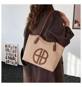 Detail of a woven tote bag with brown leather accents and circular logo on model