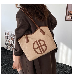Detailed woven texture and circular logo on large khaki tote bag worn by a model