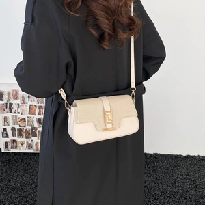 Chic cream patchwork saddle bag with gold lock and textured flap on model with black coat