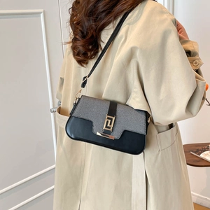 Minimalist black and grey shoulder bag with gold metal buckle shown on a model