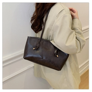 Close-up of leather shoulder bag with knot detail and embossed fashion text logo
