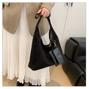 Detail of black suede hobo bag with mini coin purse accessory and gold hardware