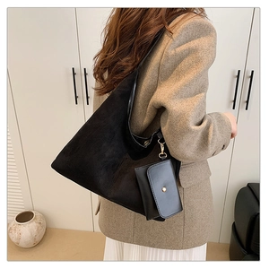 Detail of black suede tote bag with attached small pouch shown on model in beige coat