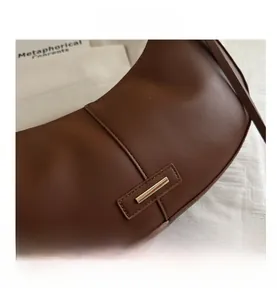 Gros plan du sac croissant marron avec texture en cuir lisse et détail de boucle dorée