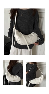 Detail of white leather crescent bag featuring sleek metallic buckle and long fringe straps