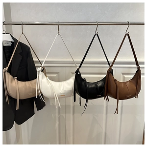 Série de sacs bandoulière en cuir demi-lune aux tons neutres avec pompons et métal