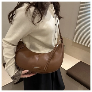 Detailed view of a brown leather crescent bag with sleek stitching and metal plate detail