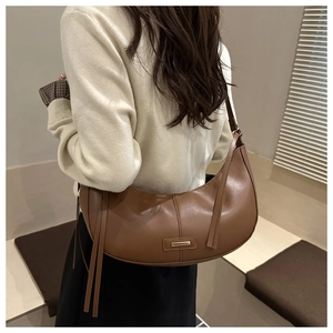 Brown leather crescent bag with decorative long tassels shown on model back view