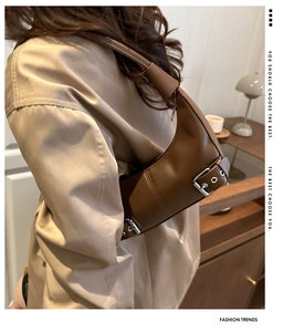 Detail of brown leather hobo bag with silver metal buckle side accent and smooth finish