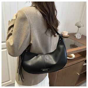 Detail of black faux leather hobo bag with tassel accent and metallic logo plate