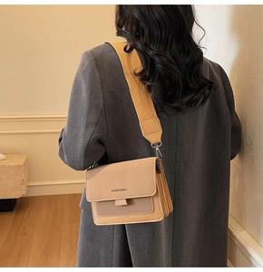 Detail view of stylish color-block crossbody bag with wide strap on a wool coat