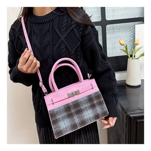 Detail of pink leather and checkered fabric crossbody bag with metal twist lock closure
