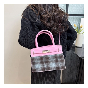Detail view of the pink and plaid leather handbag with silver turn-lock and strap