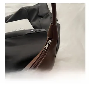 Close-up of smooth silver metal zipper on dark brown leather shoulder bag detail