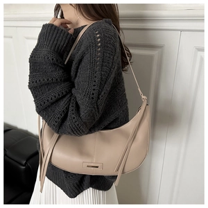 Détail du sac hobo beige avec une fermeture à glissière à pompon et boucle métallique