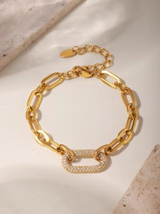 Détail macro du bracelet à maillons dorés avec zircon rectangulaire et plaque gravée