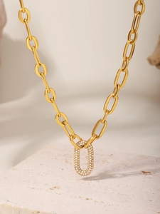 Détail d'un collier en chaîne dorée avec pendentif ovale serti de zircons blancs brillants