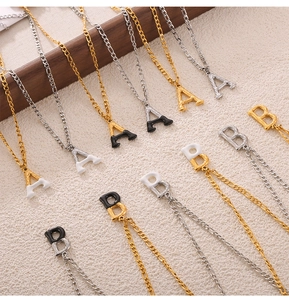 Detail of letter A and B pendants with black oil drip and textured metal on chains