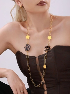 Detailed view of long gold flower chain with leopard print resin charms on model