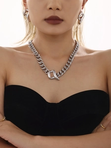 Macro shot of silver heavy-duty Cuban chain necklace and matching earrings on model
