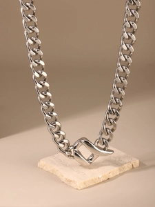 Detailed view of polished stainless steel chunky Cuban link necklace on stone base