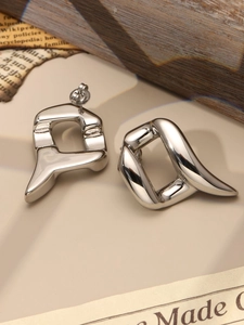 Polished silver geometric studs shown close-up on a minimalist aesthetic background