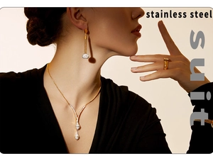Gros plan sur l'ensemble de bijoux en acier doré avec collier pendentif en V et boucles