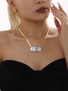 Primer plano del collar geométrico bicolor con cadena de serpiente dorada en modelo