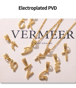Détail macro de pendentifs lettres dorés PVD avec zircons cubiques micro-sertis