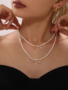 Detail of layered white pearl necklace with gold heart zircon and pearl pendants