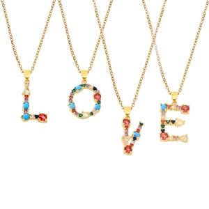 Parure de colliers dorés avec zircons colorés épelant LOVE sur un fond blanc épuré