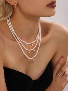 Three-layer pearl choker necklace with gold pendants and sparkling zircon accents