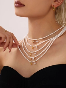 Detailed view of layered pearl choker necklace with gold pendants and crystal accents
