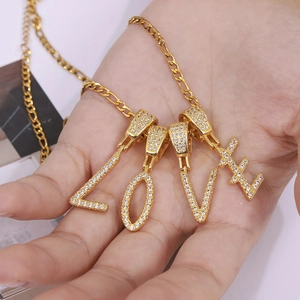 Collier à lettres LOVE doré avec zircons micro-pavés tenu dans la main pour femme
