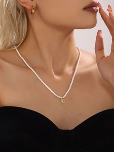 Dettaglio della collana di perle con pendente quadrato dorato e orecchini in zirconia