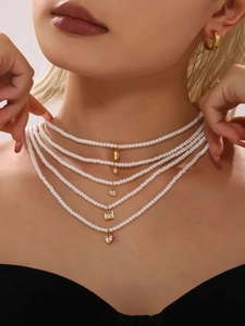 Dettaglio di collana di perle multistrato con ciondoli in zircone dorato su modella