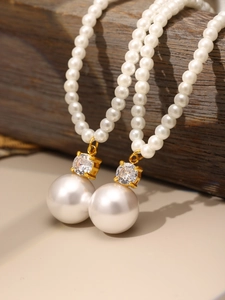 Détail d'un collier de perles double rang avec pendentifs en or sertis de zircons